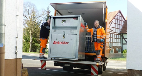 Das Foto zeigt zwei Mitarbeiter des DBM beim Ausladen eines Altkleidercontainers.