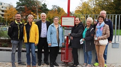 Eine Gruppe von Personen steht mit der Stadträtin um den neuen Aschenbecher an der Bushaltestelle.