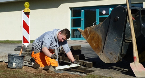 Ausbildung im Tiefbau Das Foto zeigt einen Auszubildenden des DBM beim Vermessen für Pflasterarbeiten. © DBM, Sonja Stender