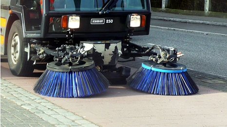 Das Bild zeigt ein Bürgersteigkehrfahrzeug im Einsatz auf einem Radweg.
