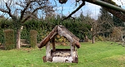 Das Foto zeigt ein Futterhäuschen aus Holz, das mit einer Handvoll gehacktenrErdnüsse bestückt ist.