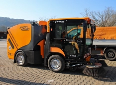 Eine orangene voll elektrische Kompakt-Kehrmaschine.