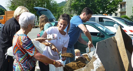 Das Foto zeigt beide Moderatoren beim Befüllen der Sandsäcke. Julia Nestle ist gleichzeitig im Gespräch mit einer Bürgerin.