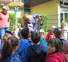 Ein Mann wiegt etwas mithilfe einer Kofferwaage. Viele Kinder schauen ihm zu.&nbsp;&copy;&nbsp;Stefanie Ingwersen, Stadt Marburg