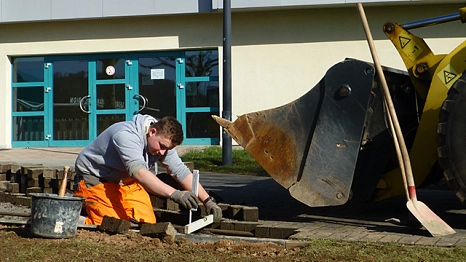 Pflasterarbeiten Das Foto zeigt einen Auszubildenden des DBM beim Pflastern eines Weges. © DBM, Sonja Stender