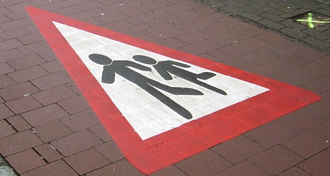 Das Bild zeigt ein "Achtung Fußgänger" Schild als Markierung auf dem Radweg.