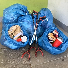 Das Foto zeigt blaue Müllsäcke aus denen Fastfood- Verpackungen herausquellen und drei Papierzangen.&nbsp;&copy;&nbsp;DBM, Sonja Stender