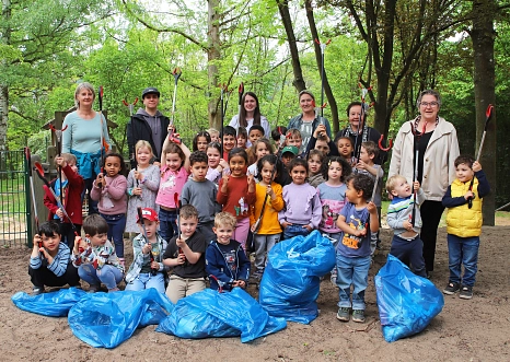 Eine Gruppe von Kindern stehen aufgestellt mit Müllzangen in der Hand in einem Wäldchen. Vor Ihnen liegen gefüllte blaue Säcke. Einige Erwachsene stehen in der hinteren Reihe.&nbsp;&copy;&nbsp;Stefanie Ingwersen, Stadt Marburg